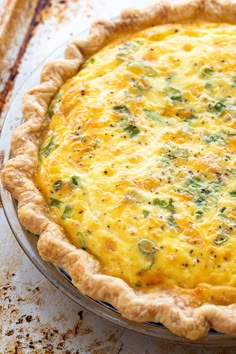 a quiche with cheese and broccoli in a pie pan on a table