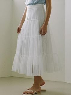 This product is a tulle layered long skirt that exudes a dreamy and ethereal quality. It features multiple layers of tulle that create a voluminous and flowing silhouette. The skirt is designed to sit at the waist, with a smooth waistband that transitions into soft, gathered tulle, offering both comfort and a flattering fit. - The skirt's multiple tulle layers add a romantic and fairy-tale like dimension to any outfit.- Its long, flowing design allows for graceful movement and an elegant appearance.- The fitted waistband ensures the skirt sits comfortably at the waist, accentuating the wearer's natural shape.- This tulle skirt is a versatile piece that can be styled up for a formal event or paired down for a casual, whimsical look. Layered Long Skirt, Graceful Movement, White Long Skirt, Flow Design, Natural Shapes, A Romantic, White Skirts, Fairy Tale, Long Skirt