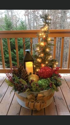 a christmas tree in a bucket on a deck with lights and decorations around the base