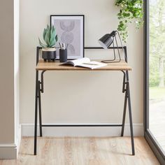 a wooden desk topped with a potted plant next to a framed photograph on top of it