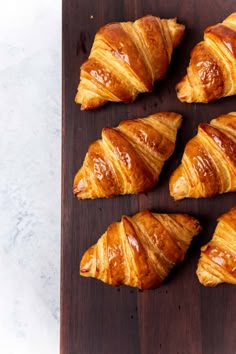 six croissants on a wooden cutting board