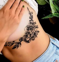 a woman's stomach with a flower tattoo on her belly and the bottom part of her lower back