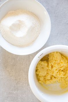 two white bowls filled with food next to each other on top of a gray table