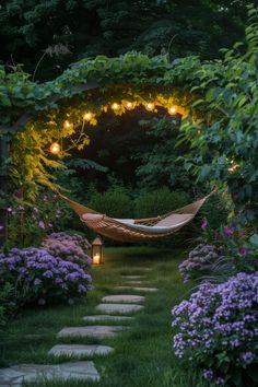 a hammock in the middle of a garden with lights strung from it's sides