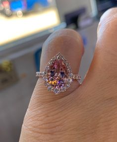 a person's hand with a pink diamond ring on it