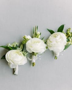 three white flowers are arranged on a gray surface