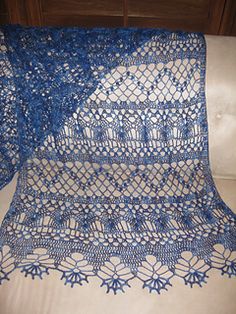 a blue crocheted doily sitting on top of a white couch next to a pillow