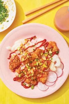 a pink plate topped with meat and veggies next to chopsticks on a yellow table