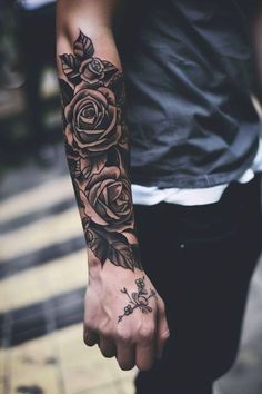 a person with a rose tattoo on their arm holding onto the hand of another person