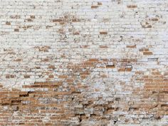 an old brick wall that has been painted white and brown with some paint chipping on it