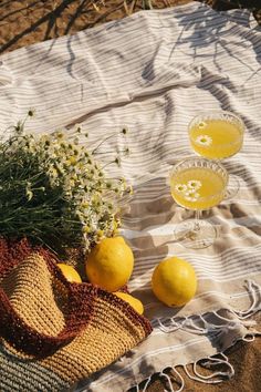 two glasses of lemonade and some flowers on a towel