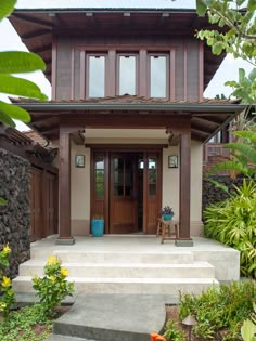 a house with steps leading up to the front door and side entrance, surrounded by tropical plants