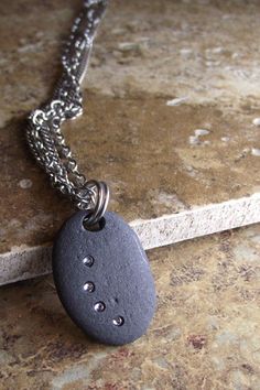 a black rock with holes in it on a chain