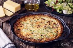 a casserole dish with cheese and vegetables in it on a table next to bread