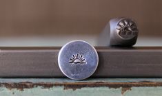 two metal buttons sitting on top of a piece of wood next to a window sill