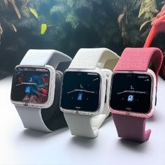 four smart watches are displayed in front of an aquarium