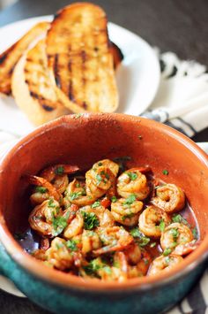 a bowl filled with shrimp next to two slices of bread