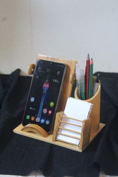 a cell phone sitting on top of a desk next to a pen and pencil holder