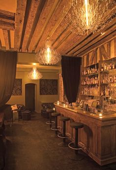 an old fashioned bar with lots of bottles on the shelves and chandeliers hanging from the ceiling