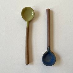 two wooden spoons and one ceramic spoon on a white surface, both with brown handles