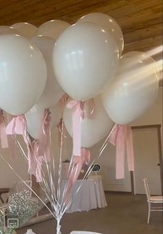 a bunch of white balloons with pink bows are on the table at a wedding reception