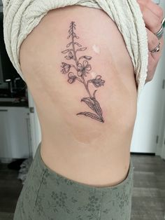 a woman's lower back tattoo with flowers on her left side ribcage