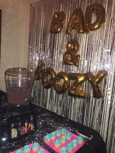 a black table topped with cake and balloons next to a glass vase filled with water