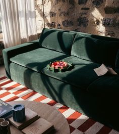 a green couch with a bowl of fruit on it