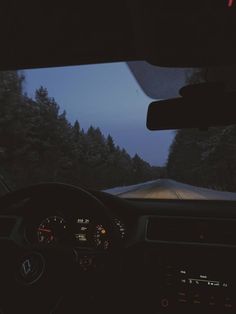 the dashboard of a car at night with trees in the background and dark clouds overhead