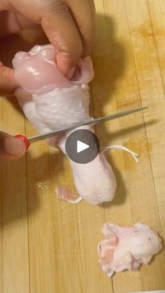 someone is cutting chicken with a pair of scissors on a wooden table and another piece of meat has been cut into smaller pieces