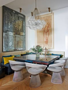 an elegant dining room with modern chairs and artwork