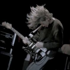 a man with long hair playing an electric guitar