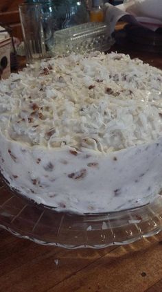 a cake sitting on top of a wooden table next to a glass plate filled with frosting