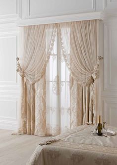 an elegant bedroom with white walls and curtains