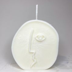 a white candle with an eye on it and a stick sticking out of the top