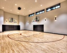 an indoor basketball court with hardwood flooring and lights on the side wall is shown