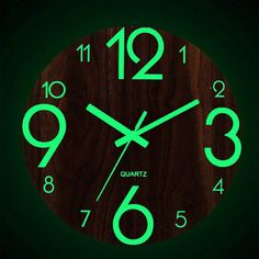 a wooden clock with green numbers on the face and hands is lit up in the dark