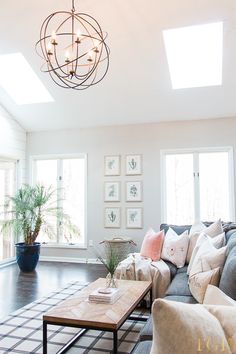 a living room filled with furniture and a chandelier hanging over the top of it