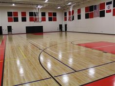 an indoor basketball court with red and black squares on the wall, in a gym