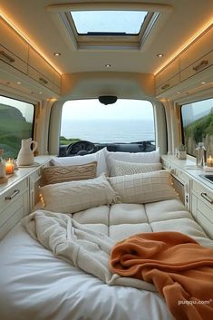 the interior of a camper van with white bedding and pillows