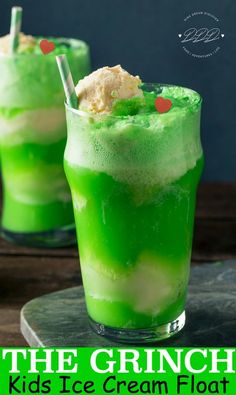 two glasses filled with green liquid and ice cream floatrs on top of a wooden table