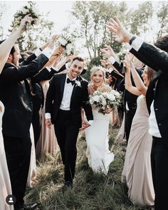 a bride and groom walking through a group of people holding their hands in the air