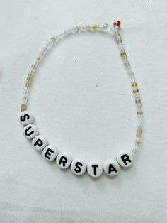 a white beaded bracelet with the word superstar on it and beads attached to it