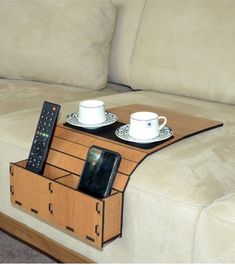 a coffee table with two cups and a remote control on it in front of a couch