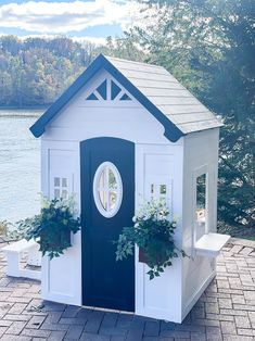 a small white and blue house with potted plants