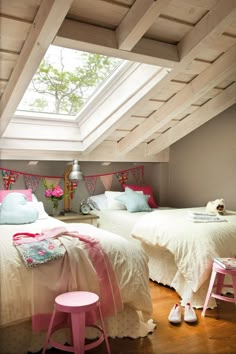 two beds in a room with skylights and pink stools on the floor next to them