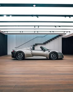 a silver sports car parked in front of a stair case on top of a hard wood floor