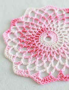 a crocheted doily with pink and white colors