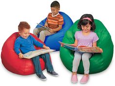 three children sitting on bean bag chairs reading books and talking to each other while one child sits on an inflatable chair