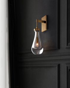 a light that is on the wall next to a black door with a gold handle